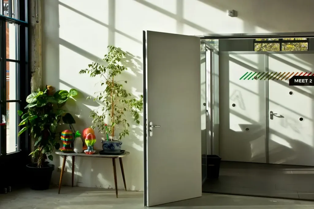 decor - office space with plants and bright windows, double open door with perspective at a meeting room door labeled meet 2 - representing insurance agency onboarding